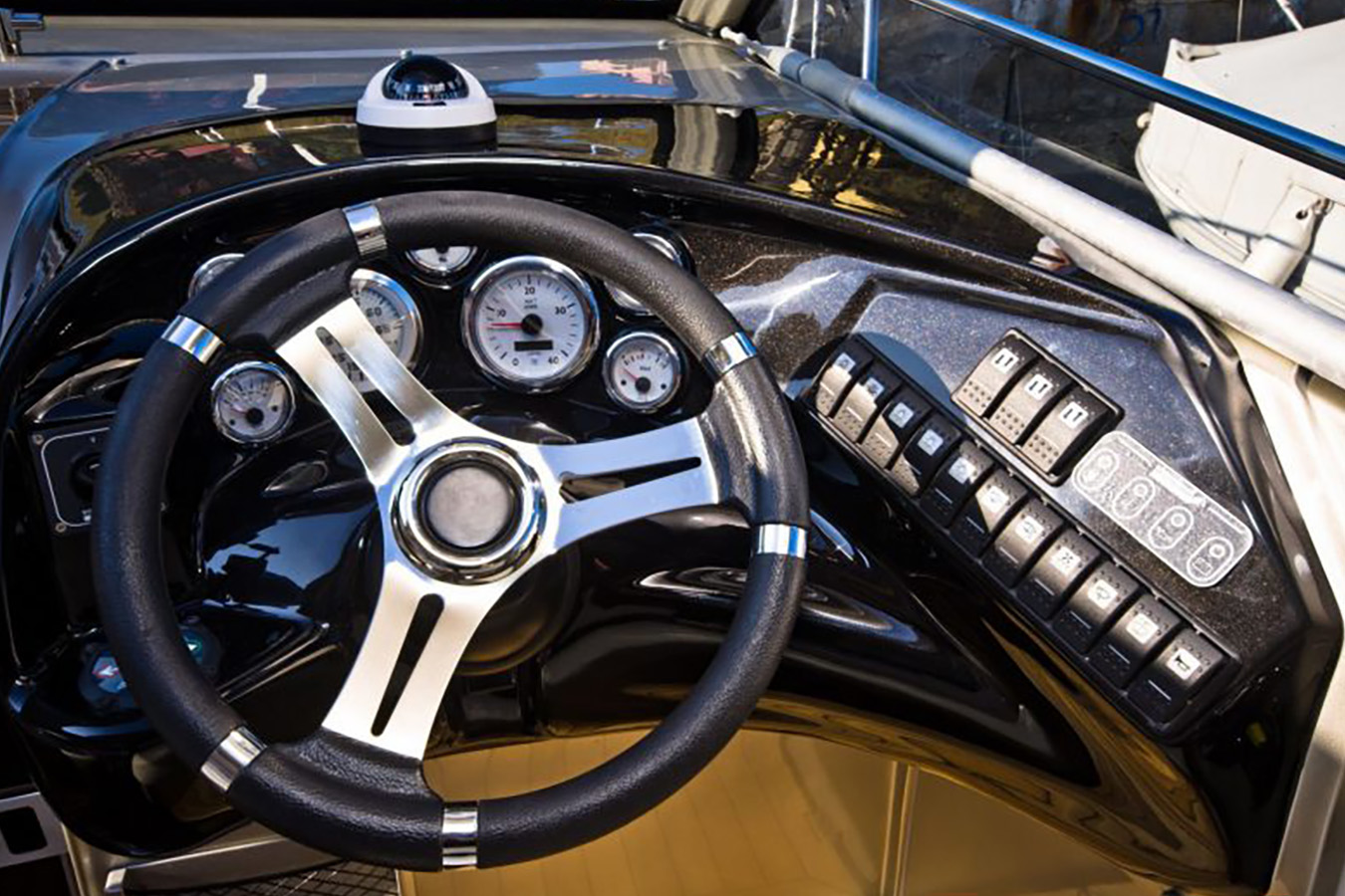 Detaljan pogled na moderni kokpit i upravljač elegantne sportske jahte, s kompasom, navigacijskim instrumentima i nizom kontrolnih prekidača