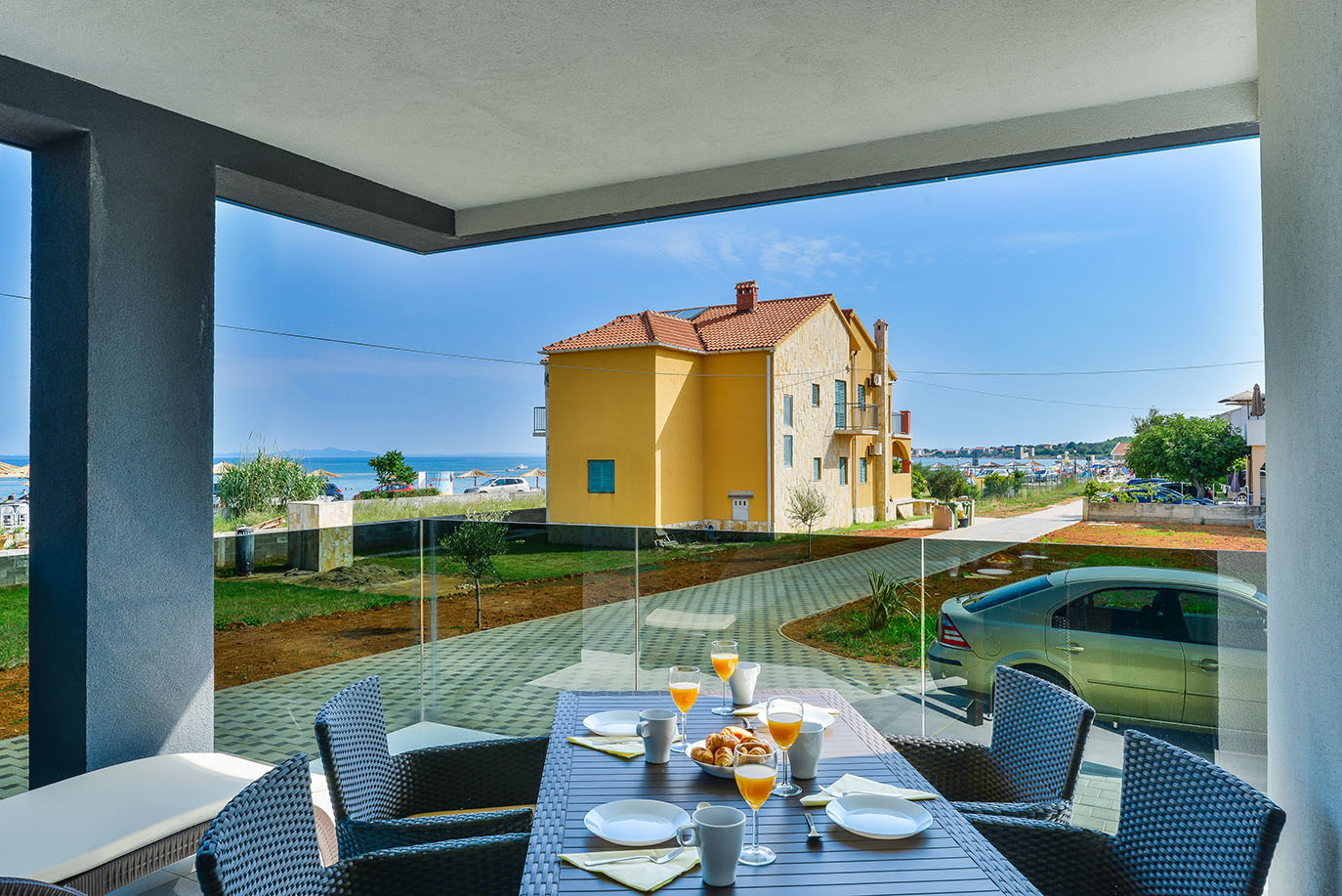 Ugodan doručak na balkonu s pogledom na more i obližnju žutu zgradu, idealan za posjetitelje apartmana Vir