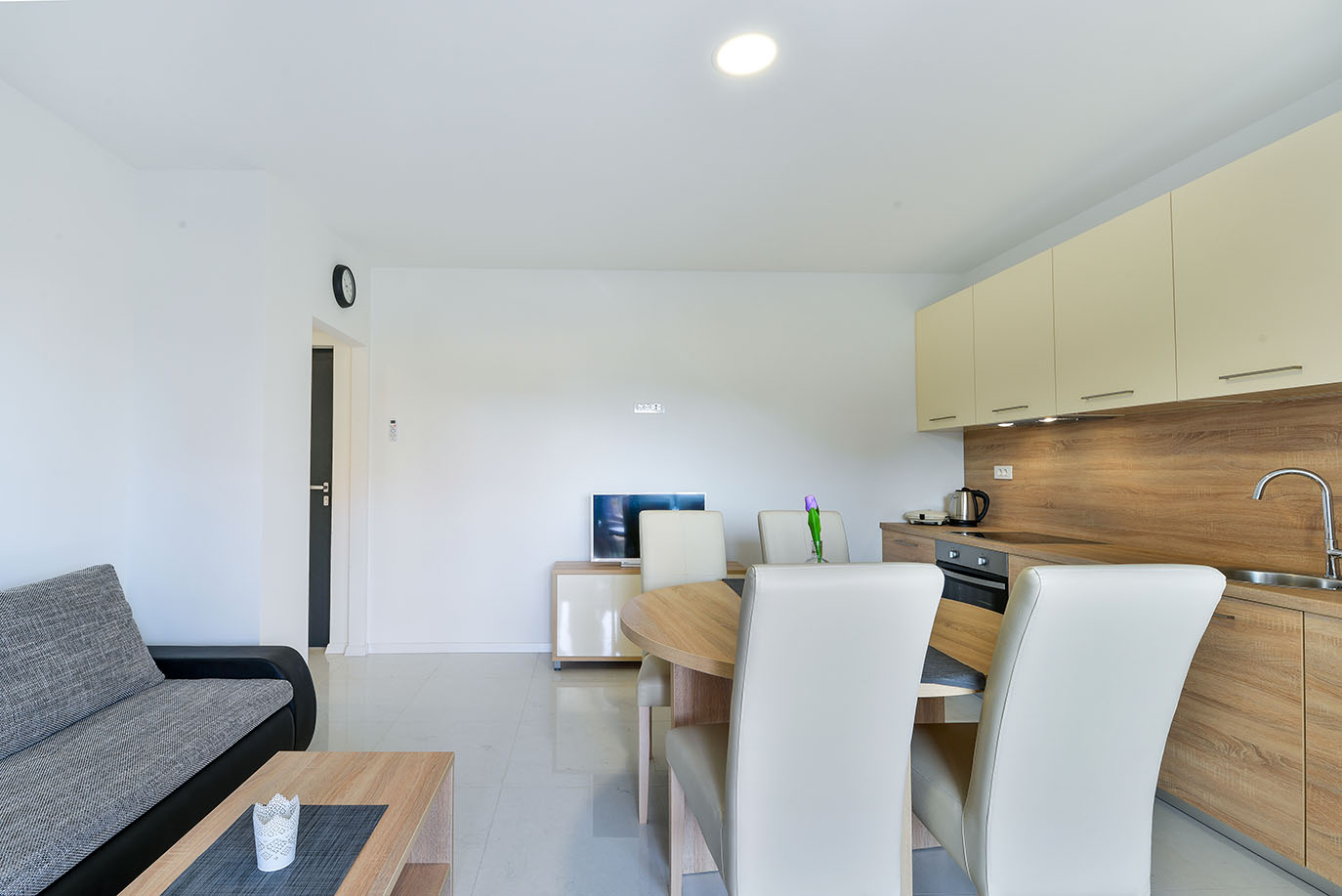 Prostrani interijer apartmana s elegantnom kuhinjom, stolom za ručavanje i udobnim kaučem, tipičan za apartmane Vir