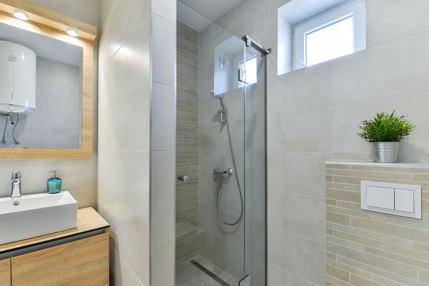 Moderna kupaonica sa staklenom tuš kabinom, kvadratnim umivaonikom na drvenoj komodi i svijetlim pločicama, što odražava kvalitetu luksuznog smještaja