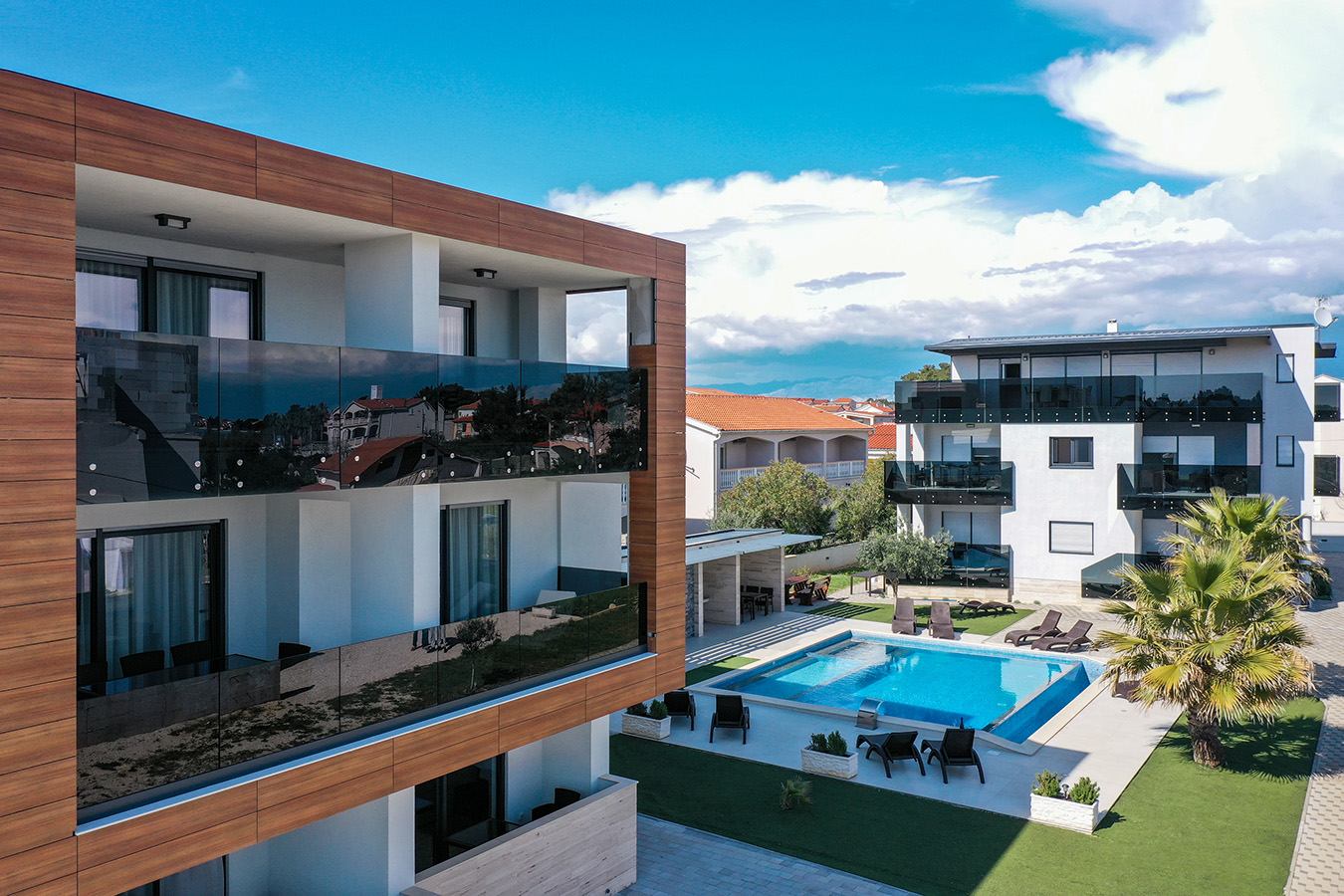 Pogled na dva objekta Resorta Mirakul s modernim balkonima i bazenom; mirno okruženje idealno za apartmane za odmor Vir