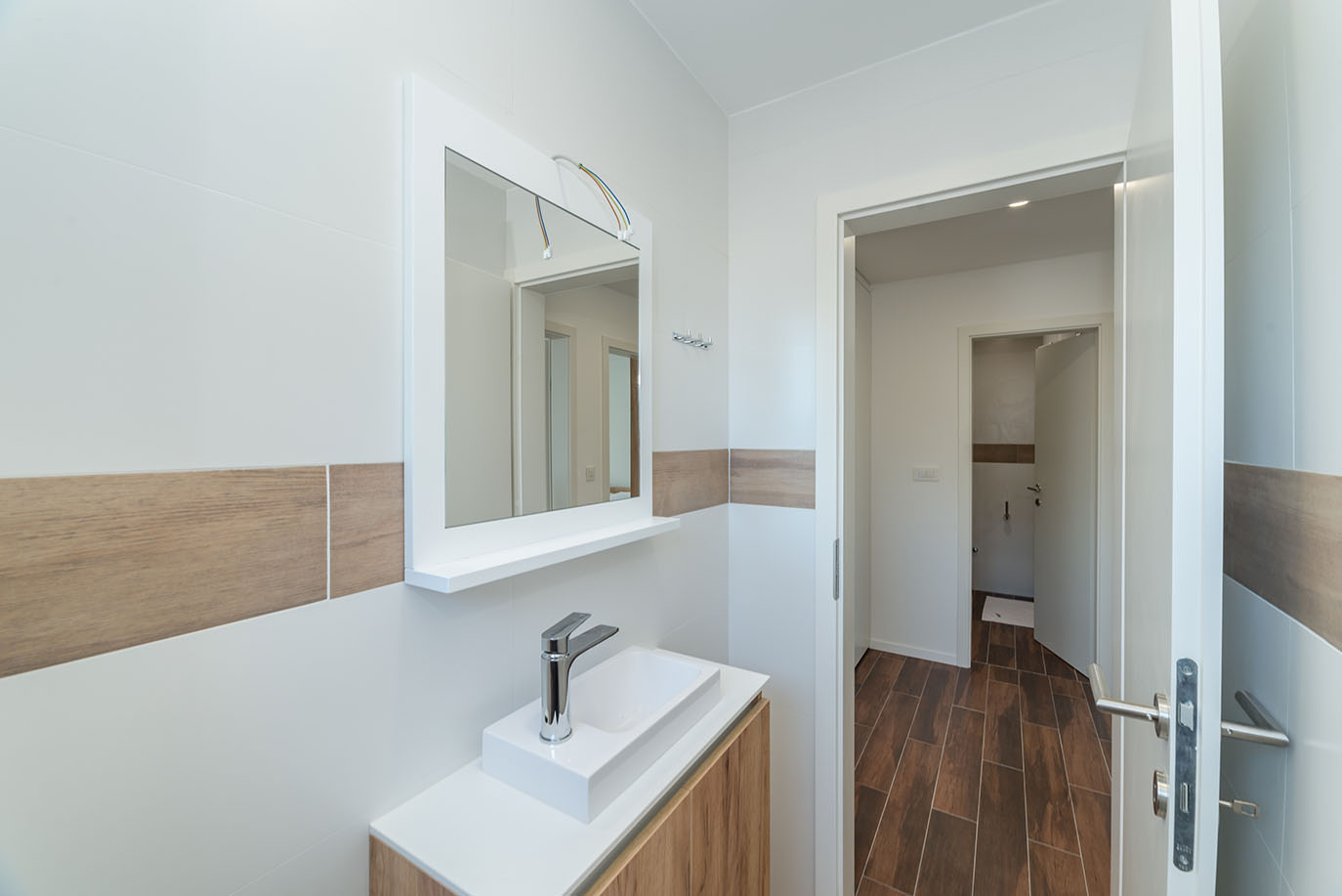 Moderna kupaonica s bijelim umivaonikom, kromiranom slavinom, drvenim ormarićem i velikim ogledalom, što odražava standard luksuznih apartmana u Hrvatskoj