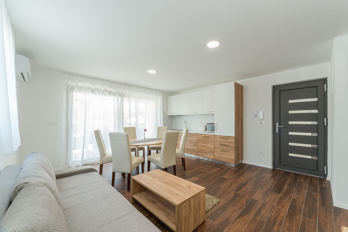 Moderan otvoreni dnevni boravak i kuhinja, idealni za ugodan boravak u apartmanima Vir, opremljeni blagovaonicom i udobnom sofom