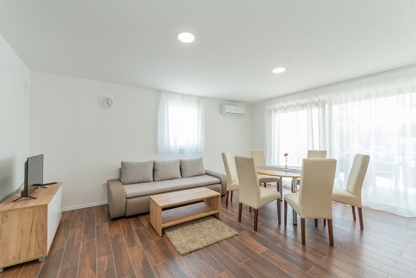 Moderan i svijetao otvoreni dnevni boravak s blagovaonicom, karakterističan za udobne apartmane Vir nudi, opremljen sofom, drvenim stolićem i blagovaonskim setom
