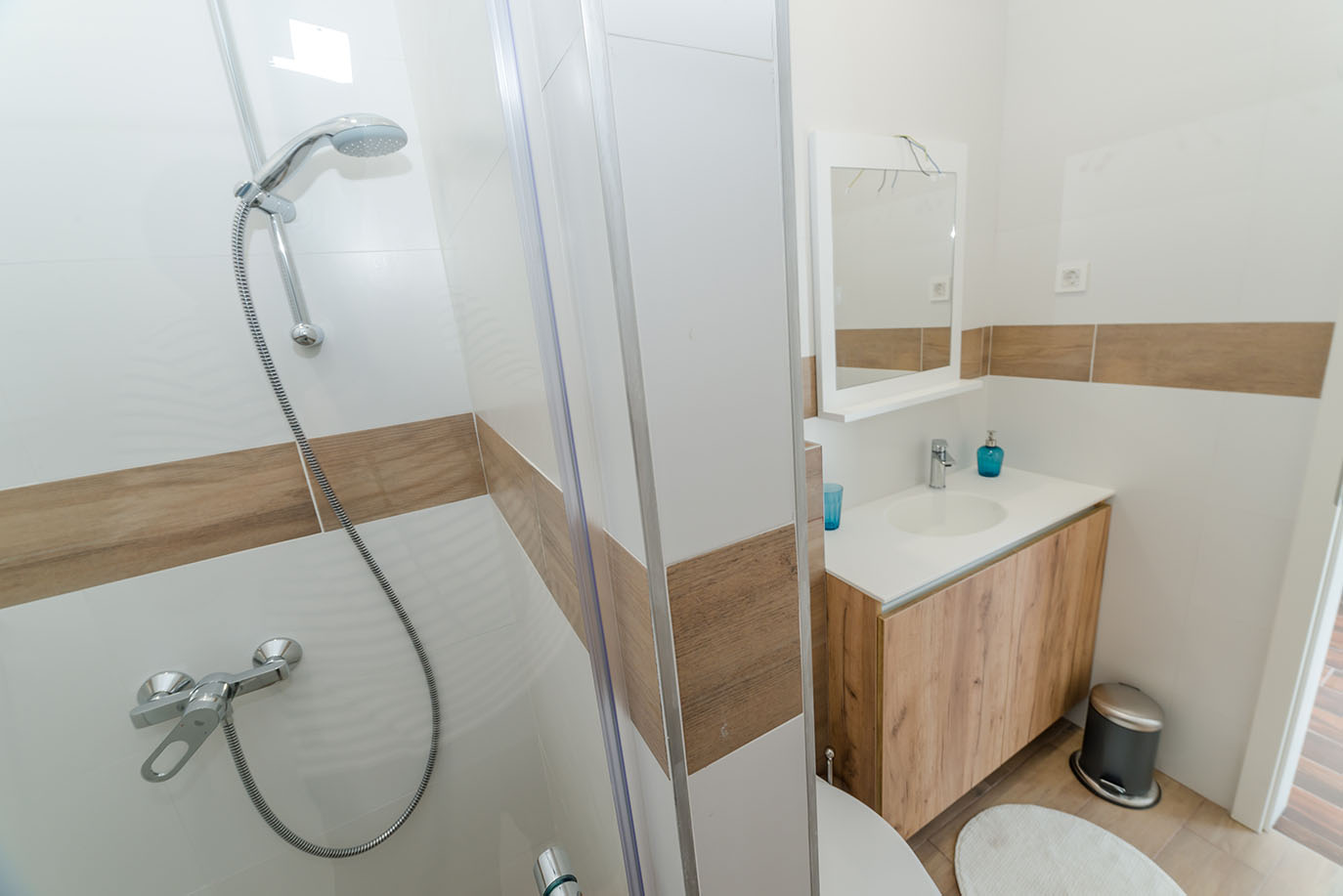 Moderna kupaonica s tuš kabinom i elegantnim umivaonikom, idealna za udobne apartmane Vir