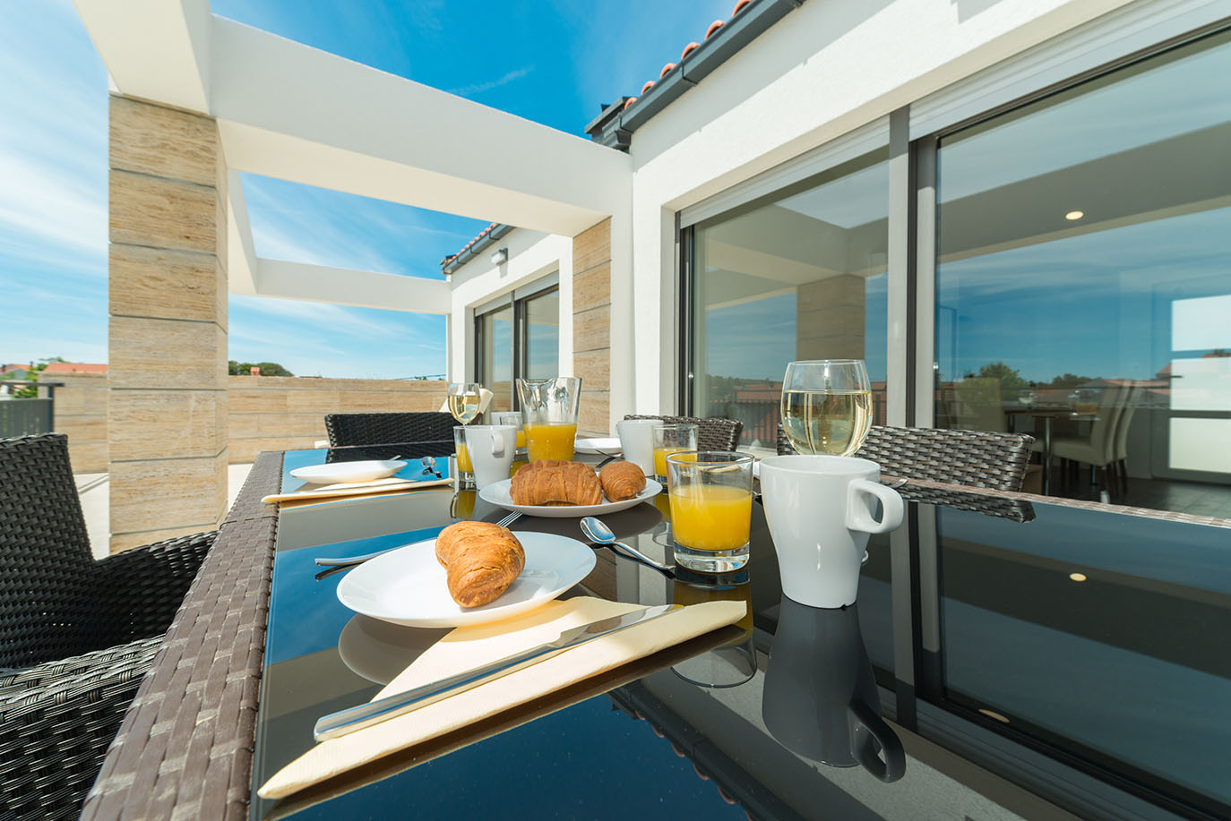 Ugodan doručak s kroasanima i sokom poslužen na sunčanoj vanjskoj terasi, idealan za opuštajući odmor u apartmanima Vir