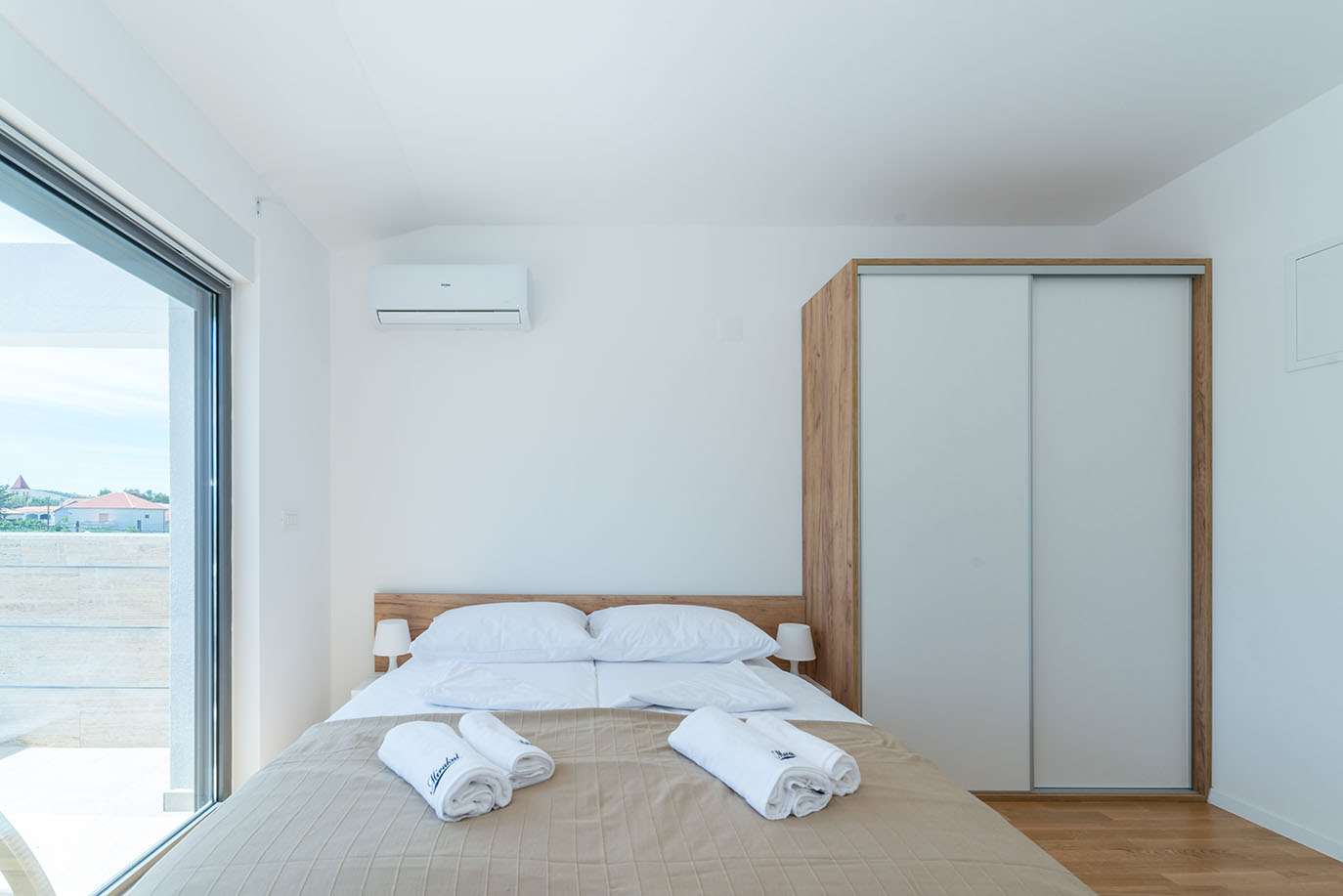 Svijetla i moderna spavaća soba s bračnim krevetom, klima uređajem i ormarom, idealna za smještaj u apartmanima Vir