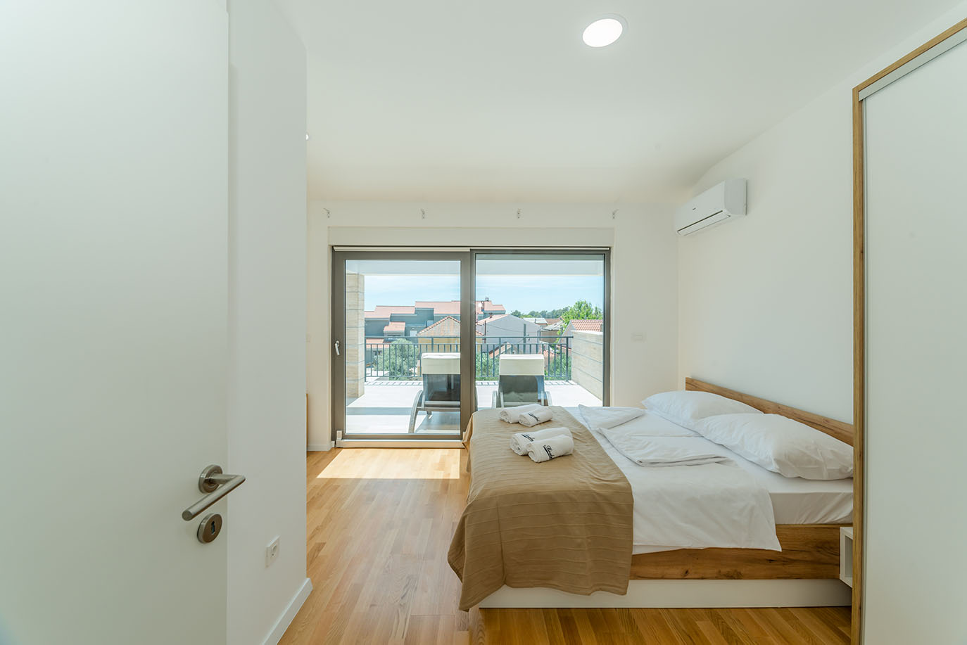 Moderna spavaća soba u apartmanima Vir s udobnim krevetom, drvenim podom i izlazom na privatni balkon